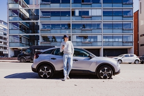 Mies seisoo 24Rentin yhteiskäyttöauton edessä kaupungissa – edullinen ja kätevä ratkaisu autonvuokraukseen matkalla ja arjessa