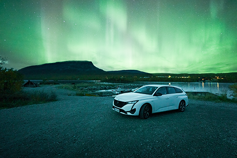 Henkilöauto revontulien valaisemana.